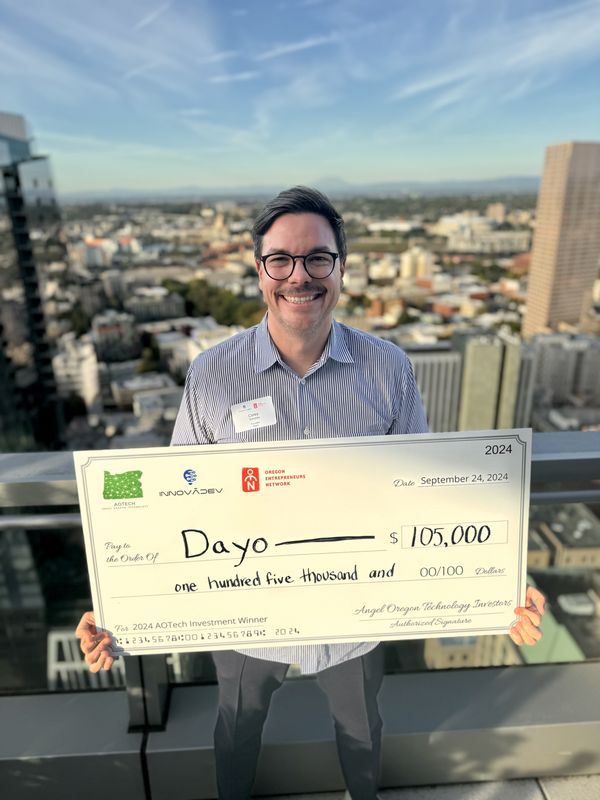 Corey holding $105K AOTech investment check for Dayo